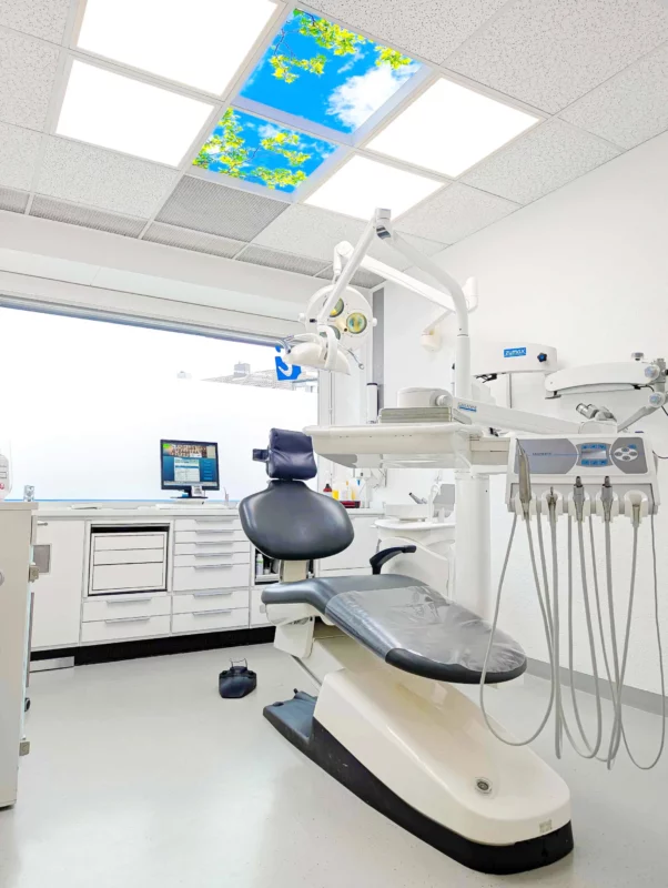Dental chair beneath calming nature ceiling panels and DL62 daylight LEDs in a modern treatment room at Zahnarztpraxis Dr. Grünewald.